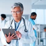 Doctor with stethoscope using a tablet in a hospital.