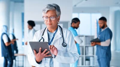 Doctor with stethoscope using a tablet in a hospital.