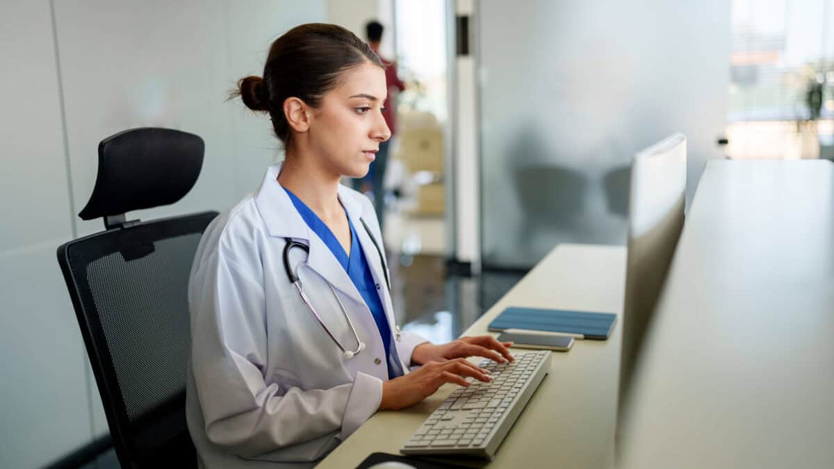 Doctor with stethoscope typing on her computer.