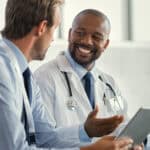Two doctors having a discussion about a patient diagnosis, holding digital tablet.