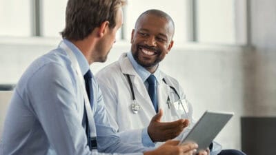 Two doctors having a discussion about a patient diagnosis, holding digital tablet.