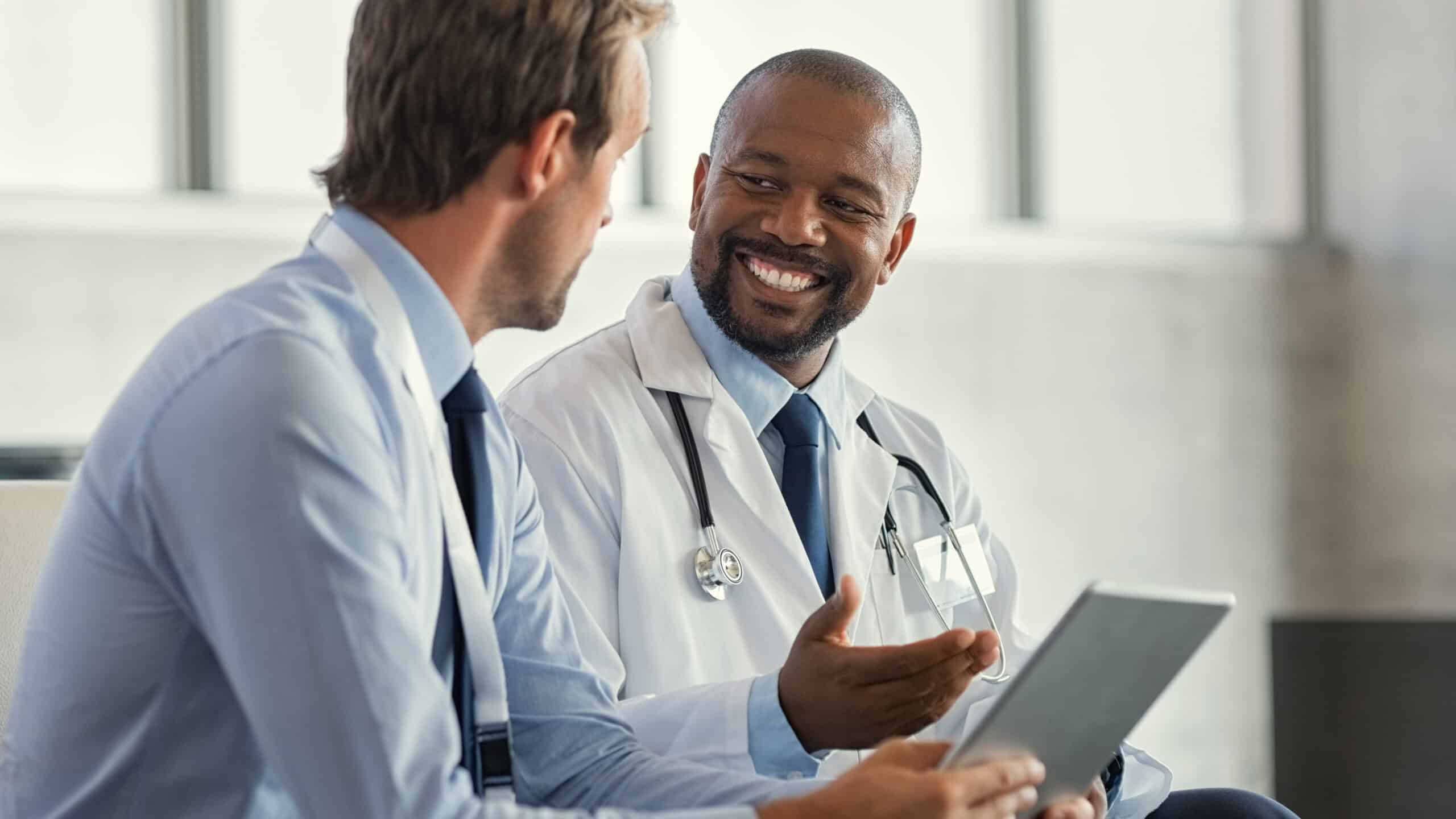 Two doctors having a discussion about a patient diagnosis, holding digital tablet.