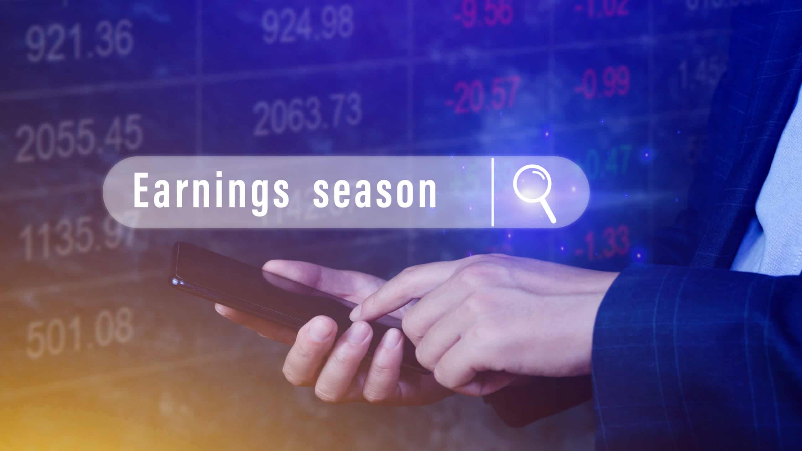 Hand touching smartphone with earnings season written in a search bubble above.