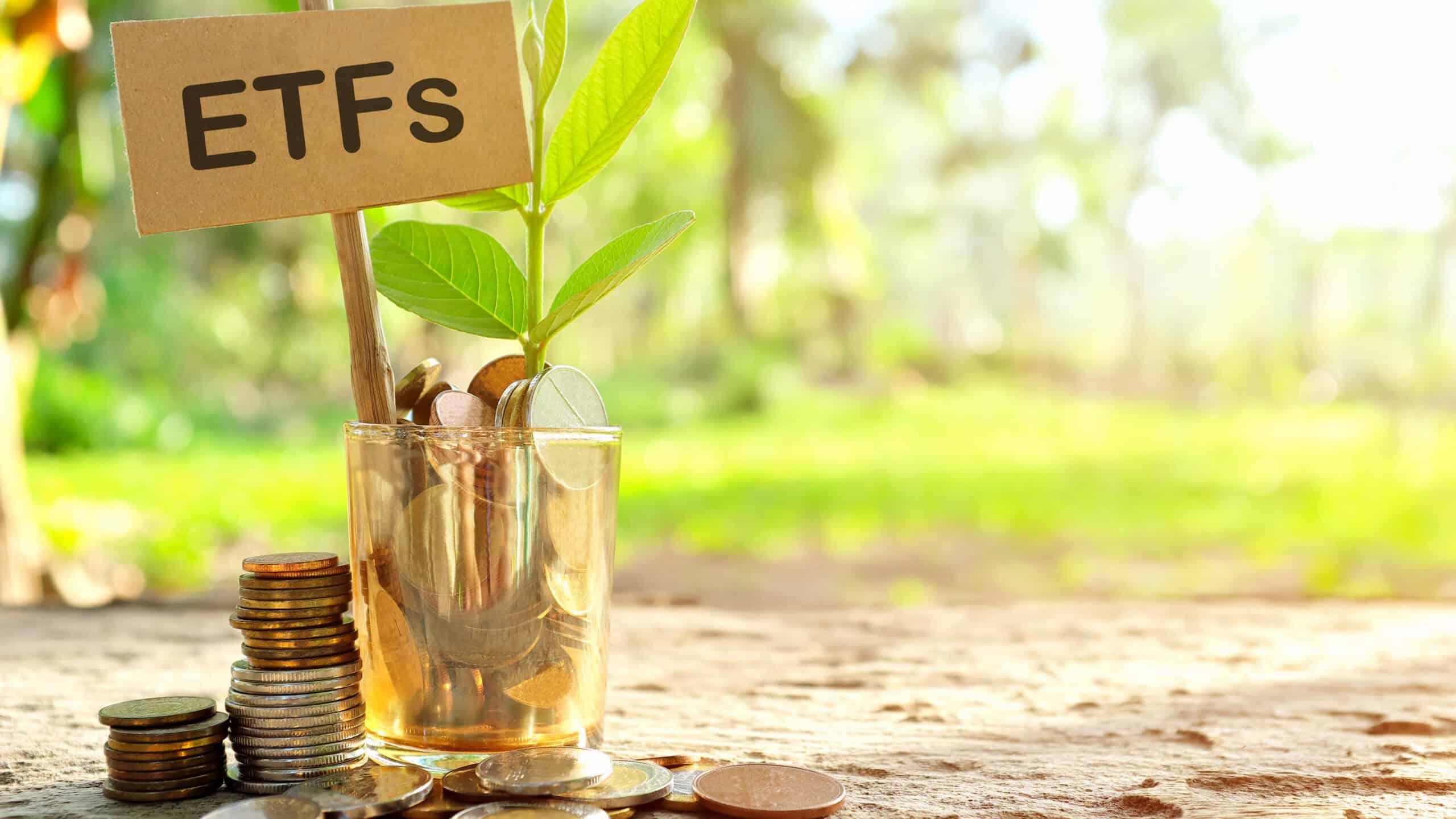 A glass outdoors with a sign with ETFs written on it, as well as coins and a growing plant.