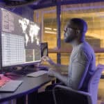 Man working on a big screen which is displaying global information about stocks with data.