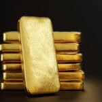 Gold bullion leaning on a stack of gold ingots.