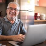 Man smiling ahead while working on his MacBook.