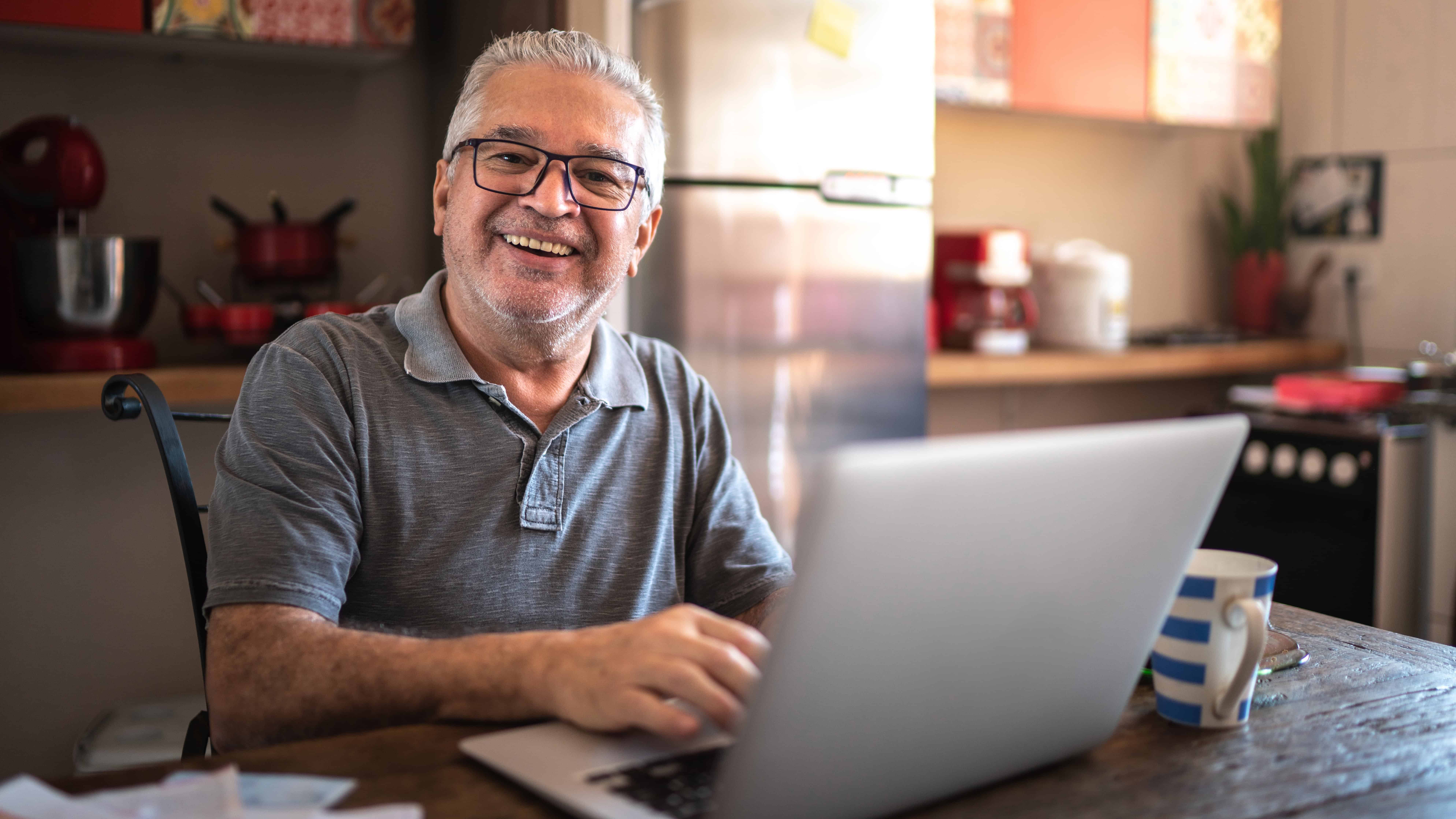 Man smiling ahead while working on his MacBook.