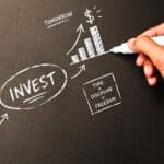 Hand sketching investment growth concept chart with chalk on blackboard.