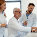 Three scientists looking at a laptop in a lab.