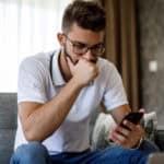 Young worried man looking at phone.