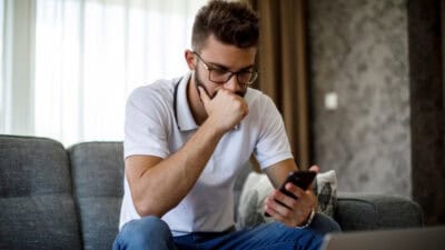 Young worried man looking at phone.