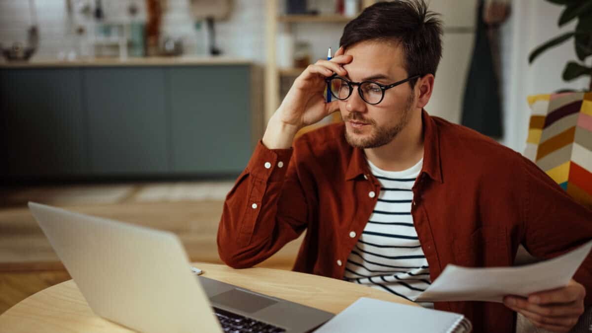 Man with hand to his forehead looking at his laptop.