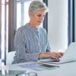 Middle-aged woman working on a laptop.