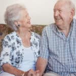 Happy senior couple sitting together hand in hand on the sofa.