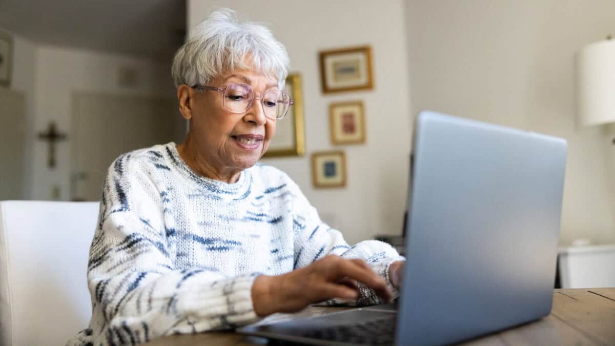 Elderly woman typing on a laptop.