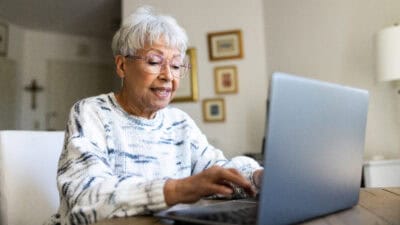 Elderly woman typing on a laptop.
