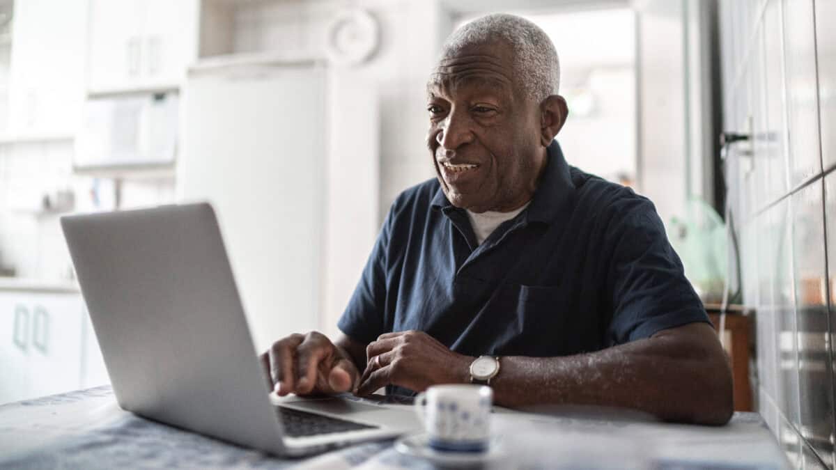 Pensioner using a laptop at his home.