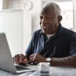 Pensioner using a laptop at his home.