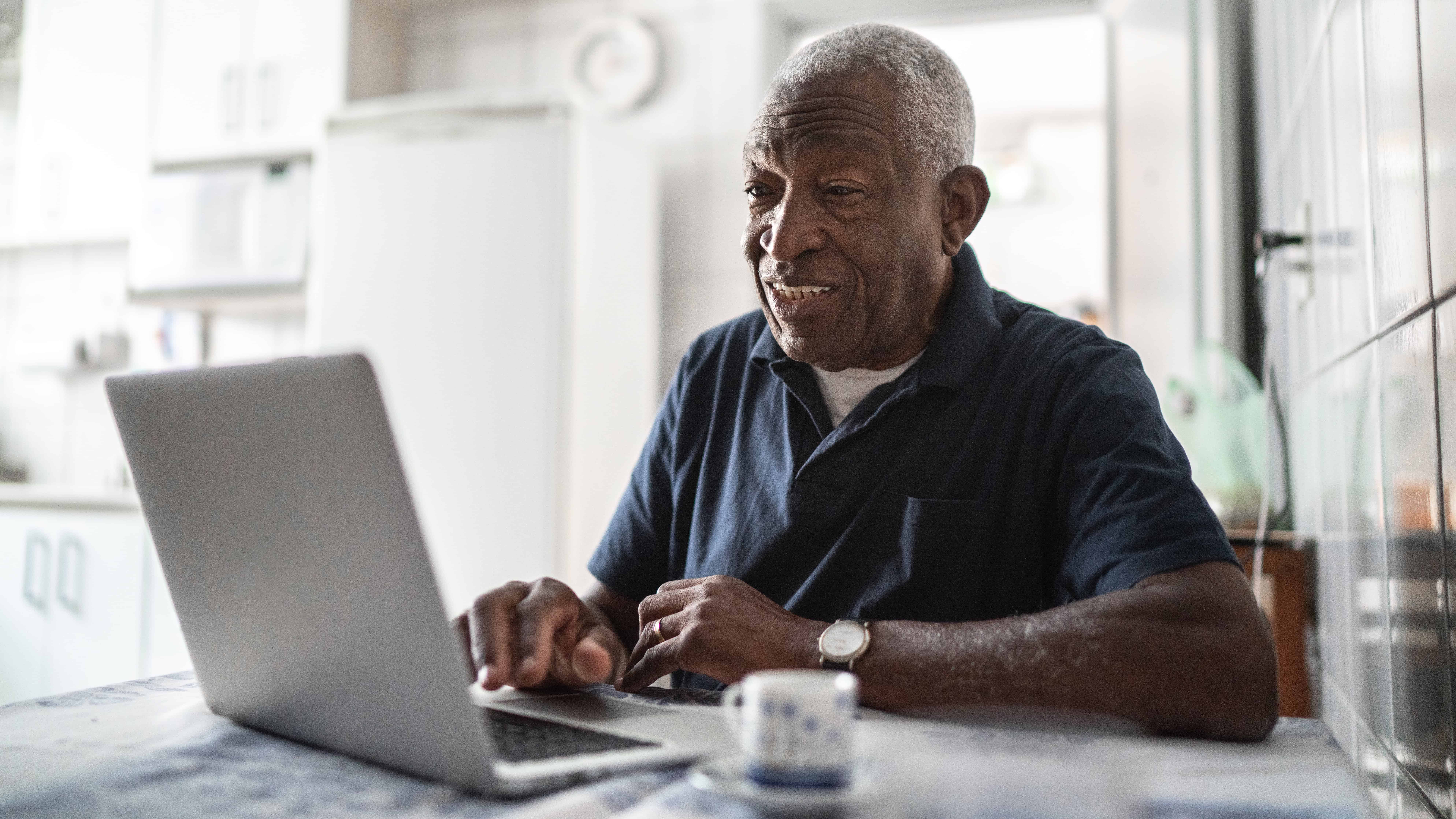Pensioner using a laptop at his home.