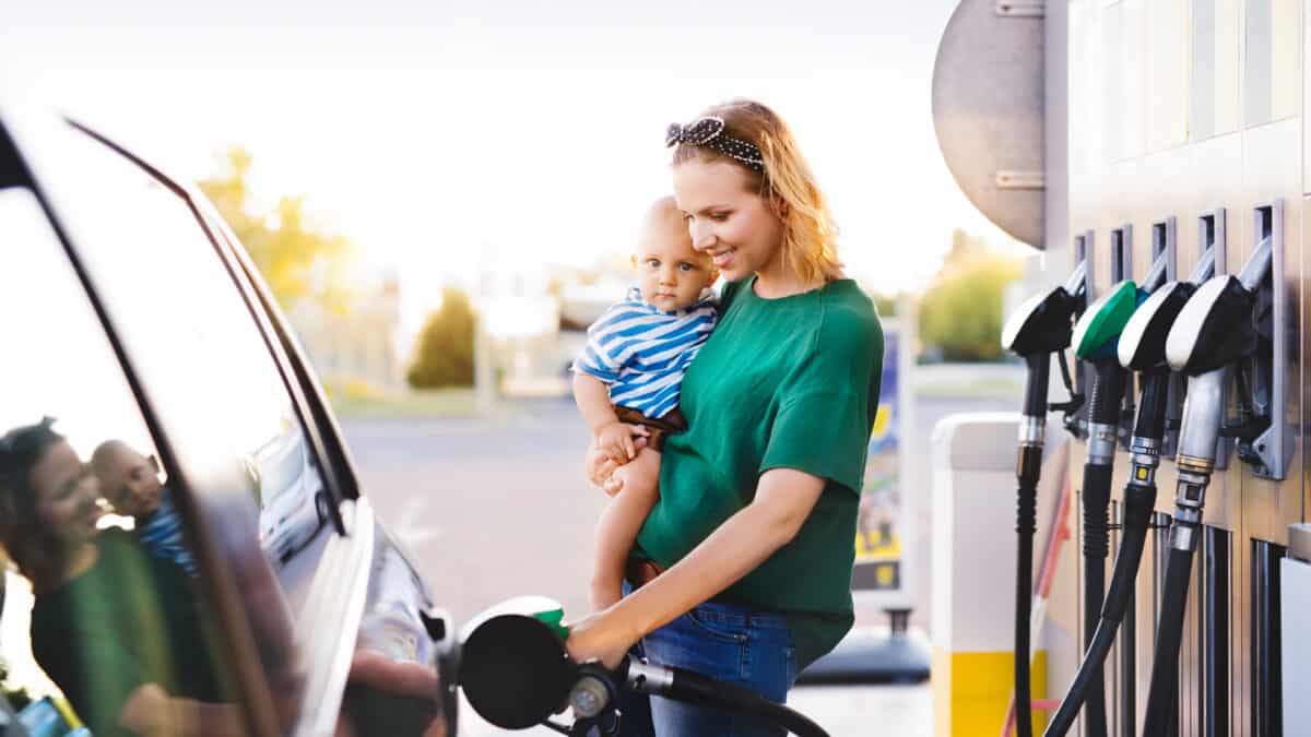 Young mother with baby boy at the petrol station refuelling the car.