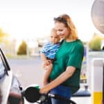 Young mother with baby boy at the petrol station refuelling the car.