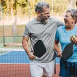 Two retirees enjoying each other's company on a pickleball court.