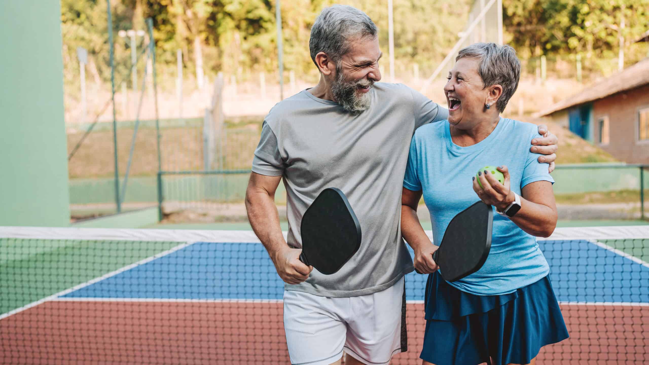 Two retirees enjoying each other's company on a pickleball court.