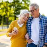 Elderly couple cosily walking together outside.
