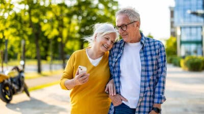 Elderly couple cosily walking together outside.
