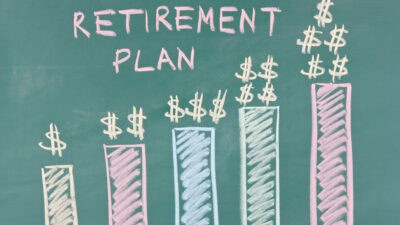 Retirement plan written on a chalkboard with increasing bar graphs and dollar signs on top.
