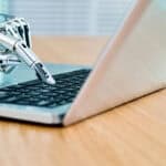 Robot's hand typing on keyboard.
