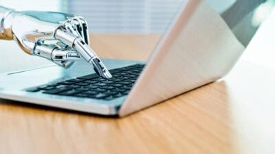 Robot's hand typing on keyboard.