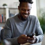 Smiling man on his phone and laptop.