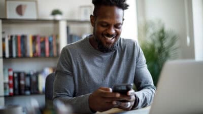 Smiling man on his phone and laptop.