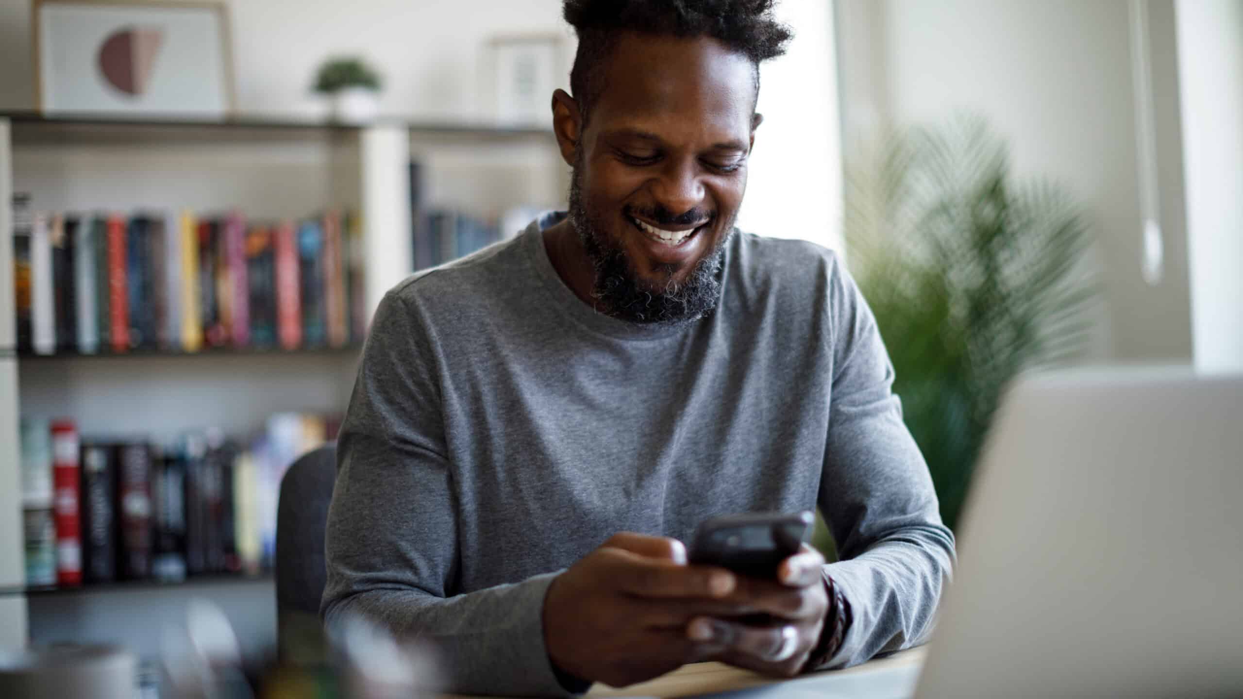 Smiling man on his phone and laptop.