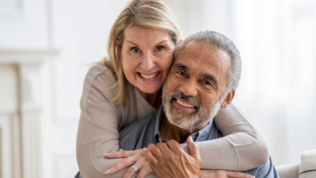 Wife hugging husband, with both smiling.