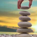 Person stacking white stones on top of one another.