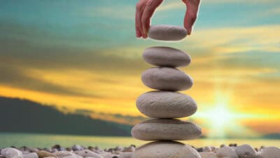 Person stacking white stones on top of one another.