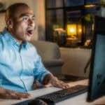 Man with a surprised expression on his face as he looks at his computer screen.