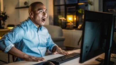 Man with a surprised expression on his face as he looks at his computer screen.