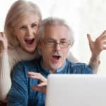 Mid-aged couple with surprised expressions on their face as they look at a laptop.