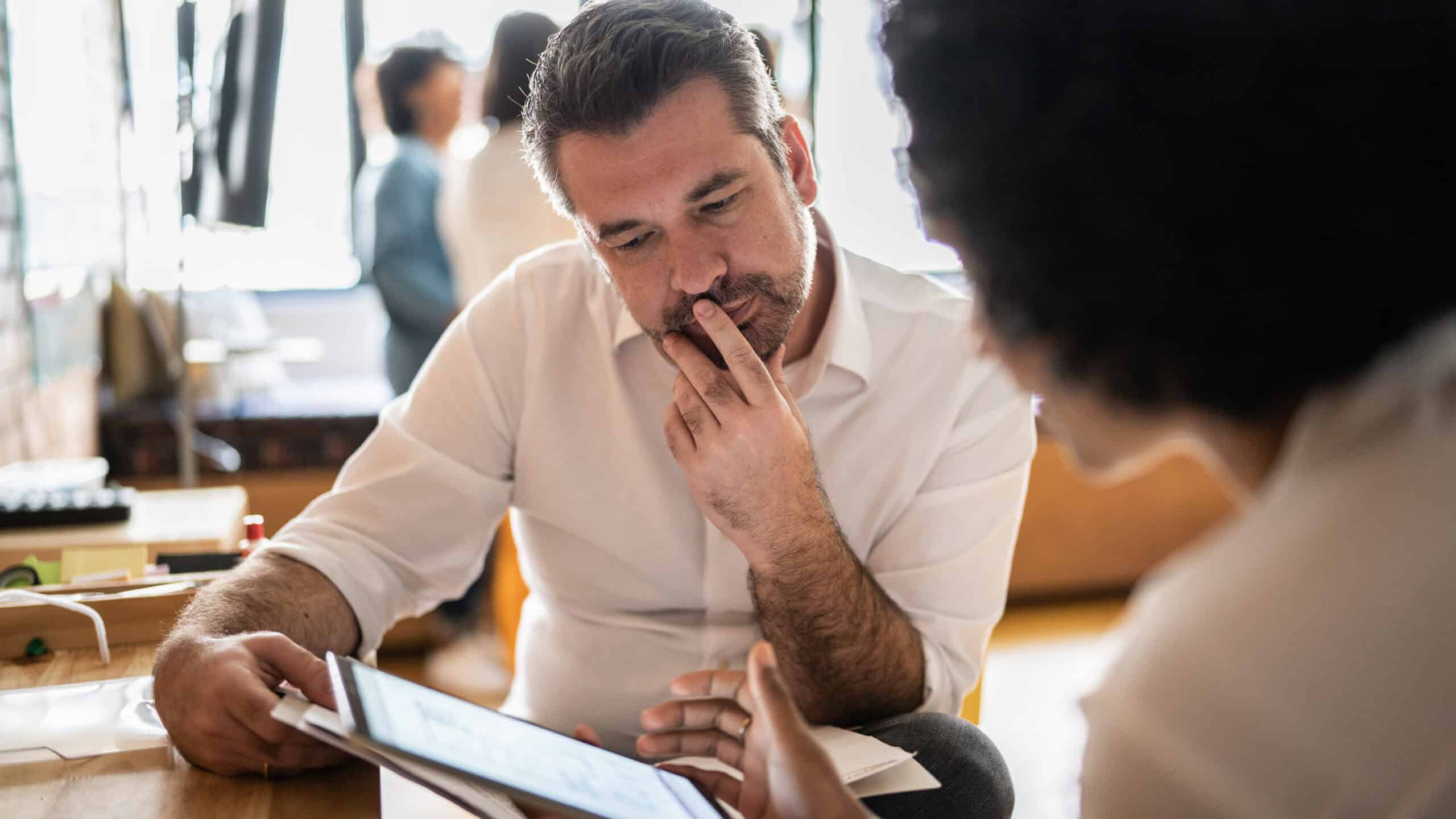 Woman and man at work looking at data on a tablet at work.
