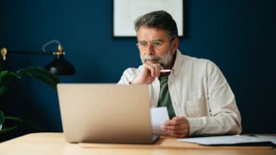 Senior man looking at his laptop and pondering something.