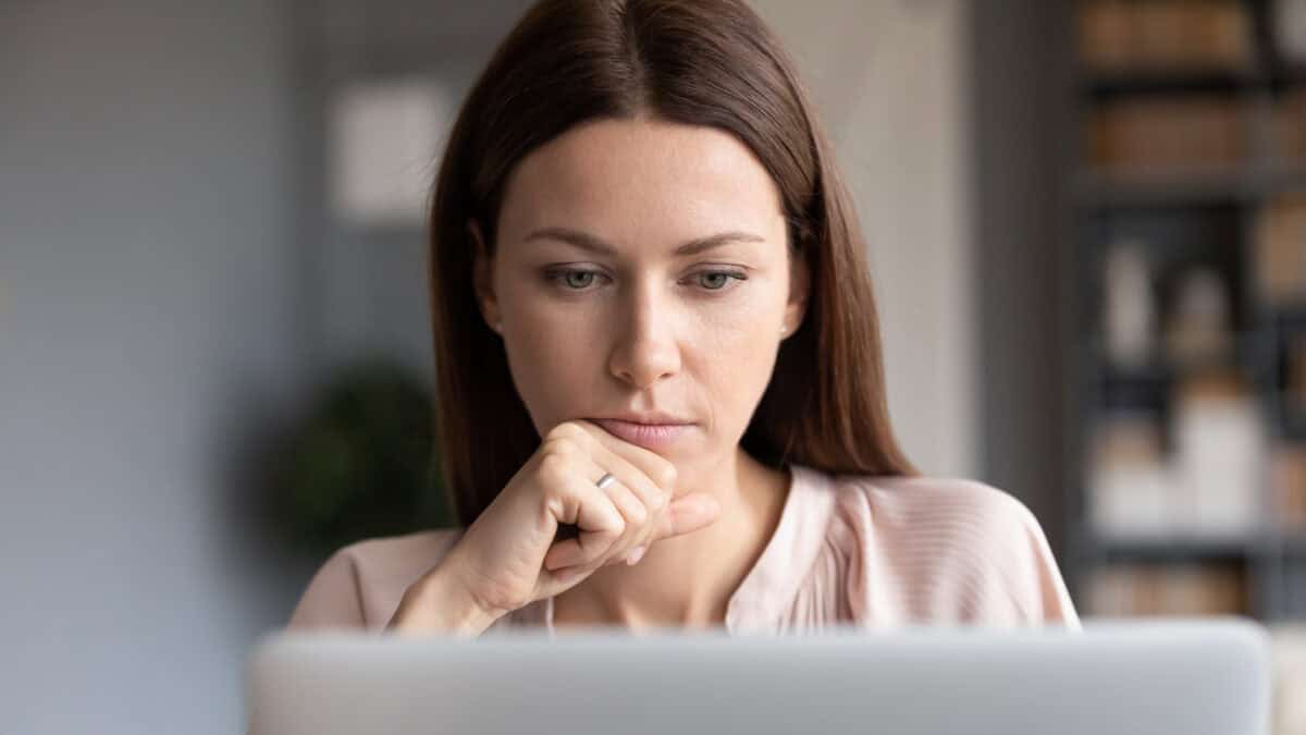 Woman looking at a laptop and thinking.