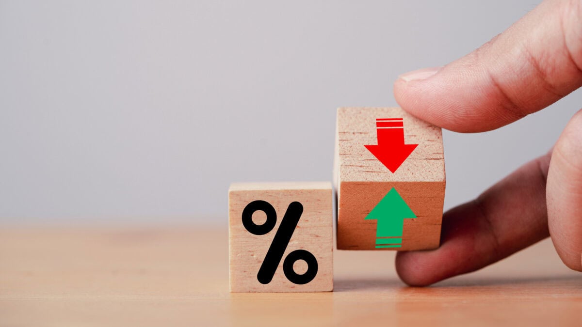 Hand flipping wooden cube block to change between up and down with percentage sign symbol next to it.