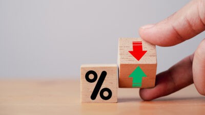 Hand flipping wooden cube block to change between up and down with percentage sign symbol next to it.