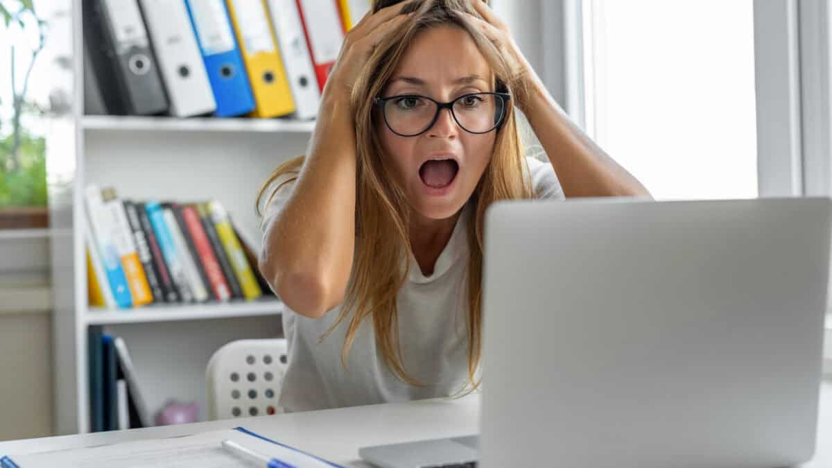 Woman screaming after looking at bad news on her laptop.