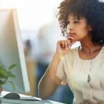 Woman looking at her computer and pondering something.