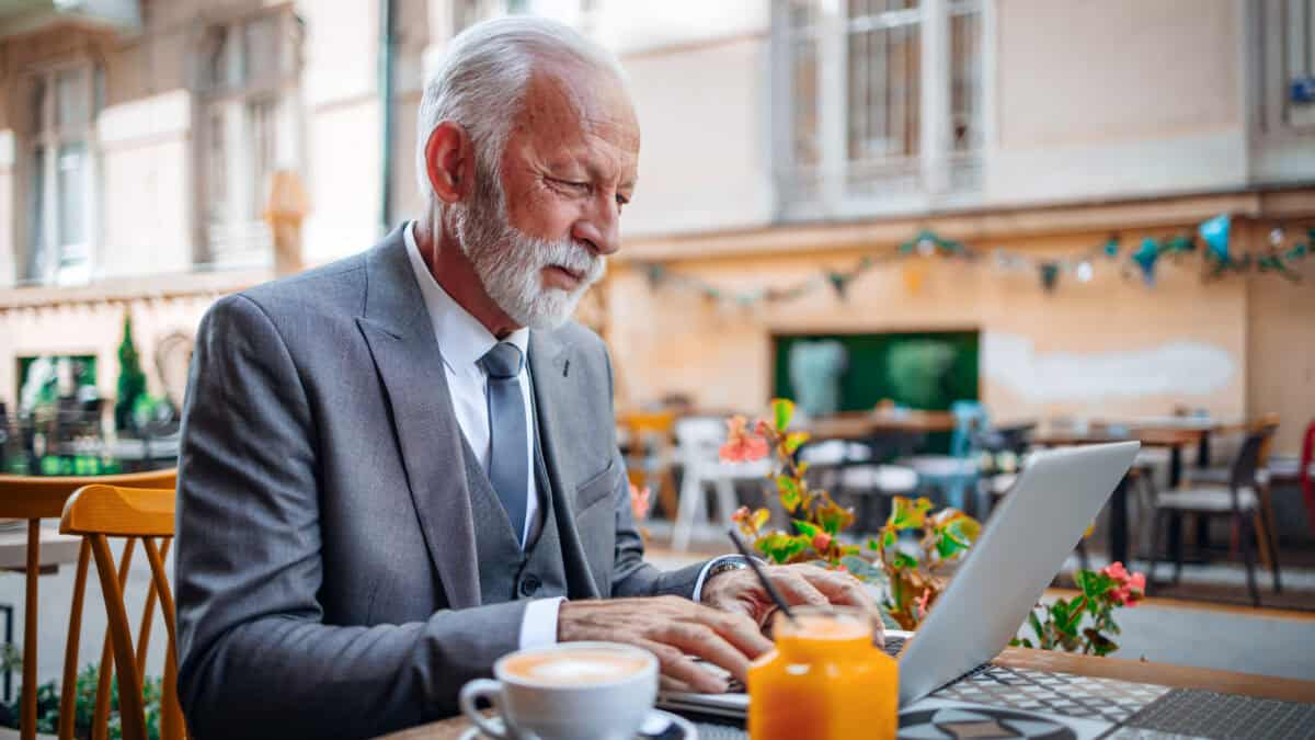 Old man working on his laptop at a cafe.